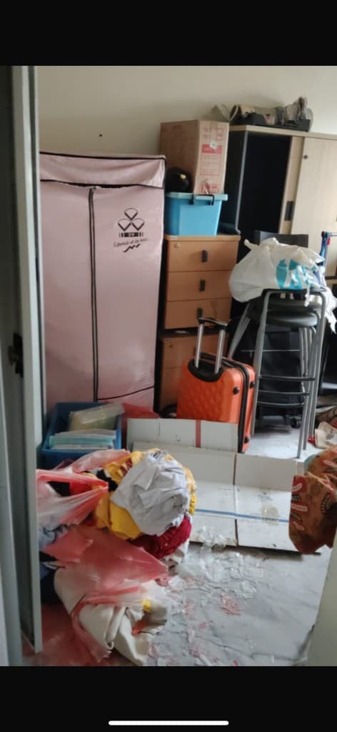 Cluttered room with wardrobe, boxes, and items before clear-out